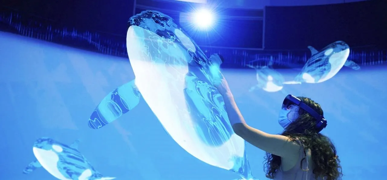 Person interacting with a virtual sea turtle in a blue, illuminated environment.