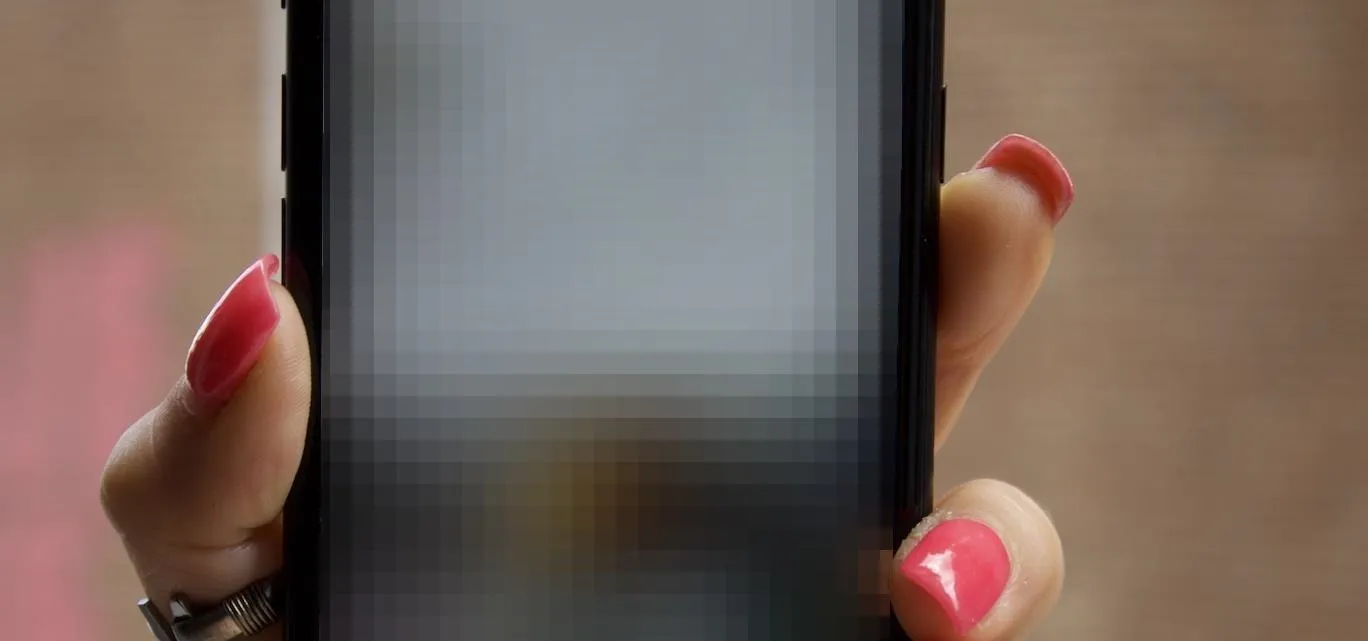 Mobile phone displaying a menu on a wooden surface.