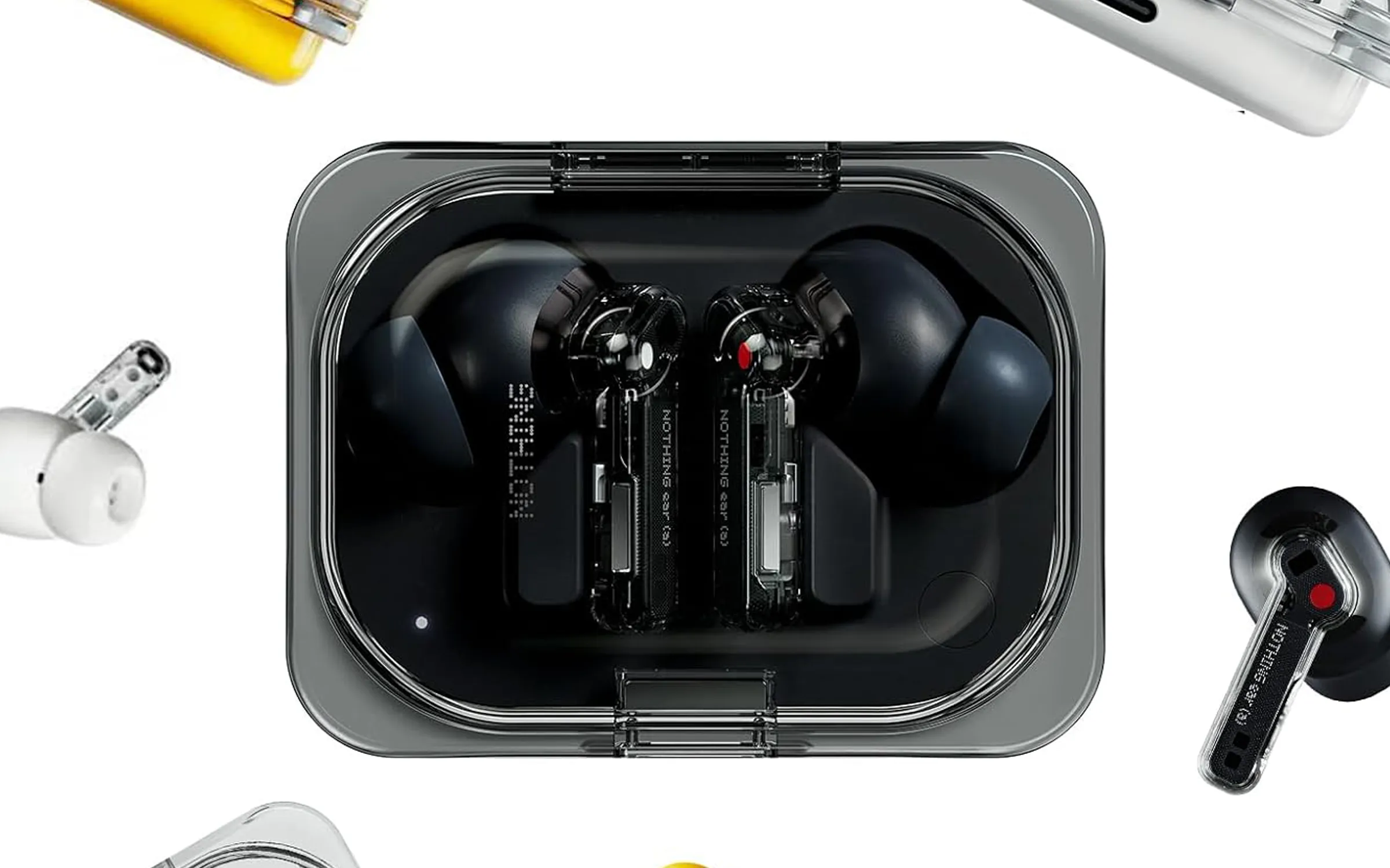 null Black Nothing Ear (a) earbuds with clear stems and red-and-white mic indicators rest inside a transparent charging case, surrounded by various other Nothing earbuds.