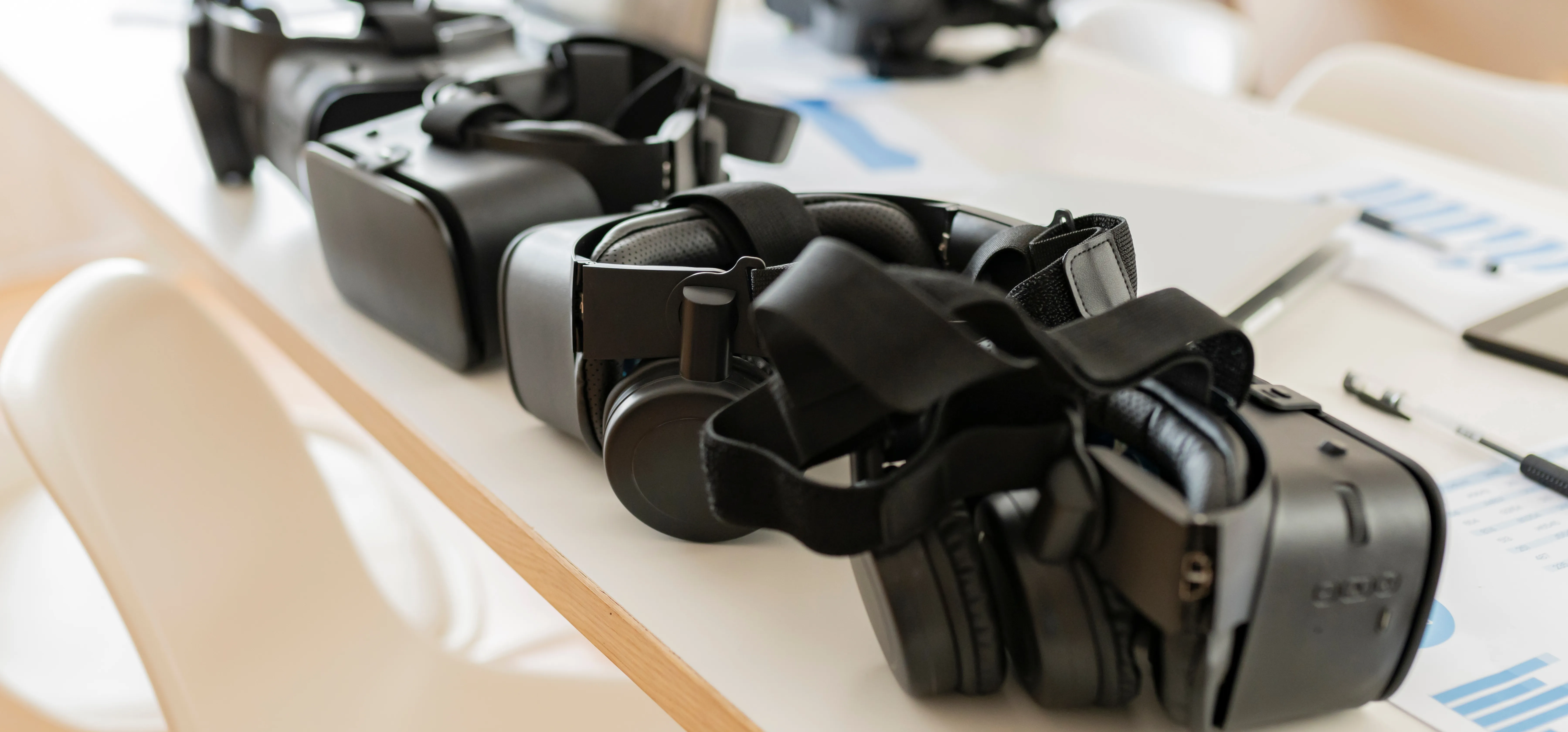 A row of virtual reality headsets on a desk in a modern workspace, highlighting the impact of tariffs on VR device production and pricing.